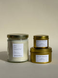Photo of Thalken’s You Are Beautiful candle shown in three vessel options — sleek gold tins (2oz and 6oz) and a soft-glow glass jar (8oz). Bright and sunny scent profile with notes of white tea, mango, and coconut.