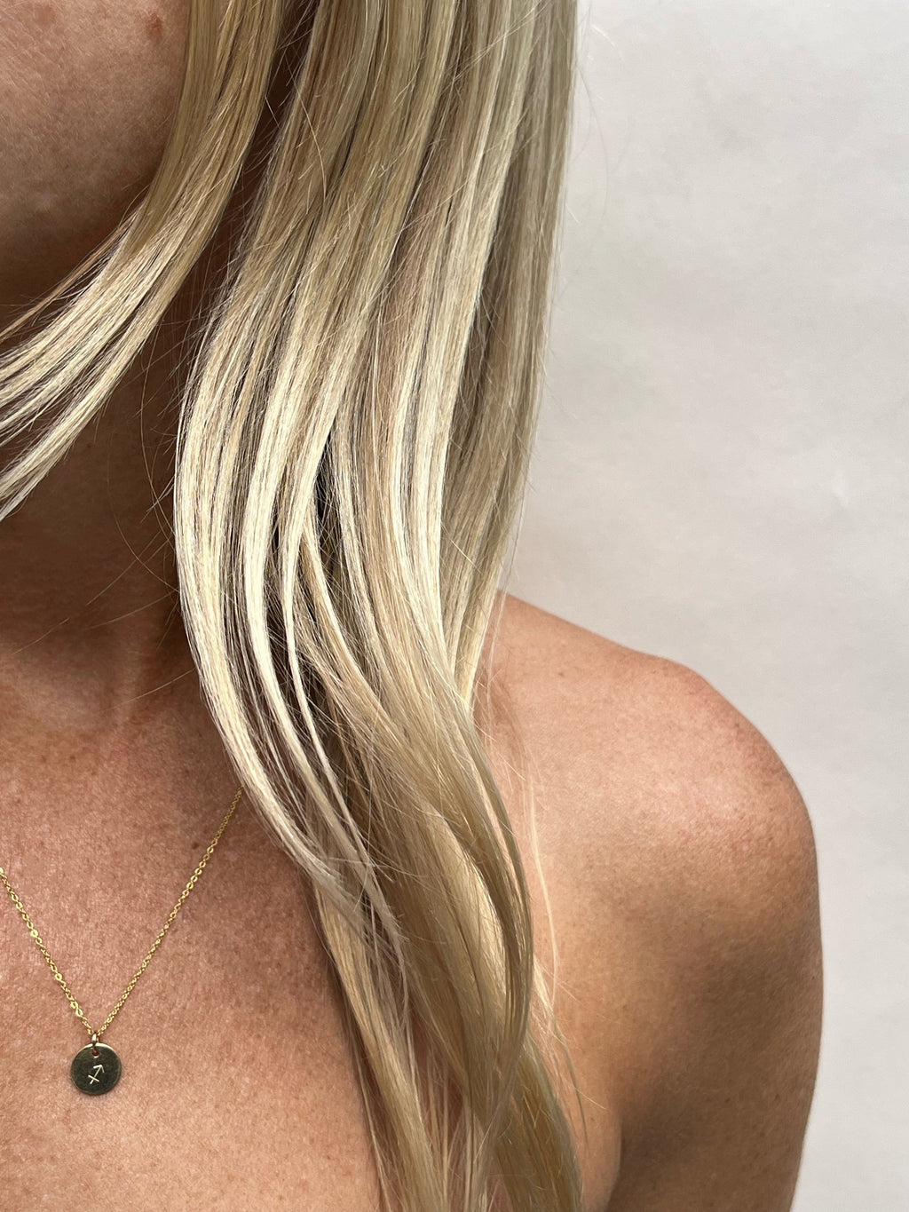 Close-up of model wearing a dainty 9mm Sagittarius zodiac disc charm on an 18" yellow gold-filled chain by Thalken